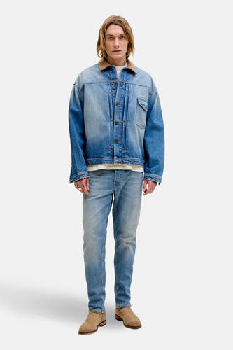Tapered mid-blue denim jeans van JACK & JONES JEANS INTELLIGENCE, gedragen met een denim jas en suède laarzen.