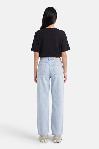 Lichtblauwe denim straight jeans van JJXX, gezien van achteren, met een zwarte t-shirt en crèmekleurige sneakers.