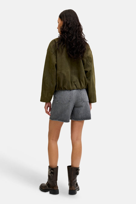 Donkergrijze denim short van JJXX met rafelige zomen, van achteren gezien, gedragen met groen suède jack en bruine laarzen.