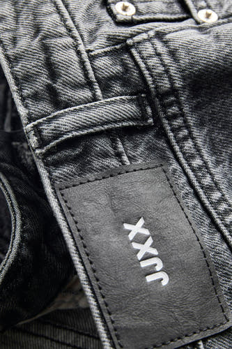 Donkergrijze denim korte broek van JJXX met zwart leren label, wit logo en zichtbare knopen.