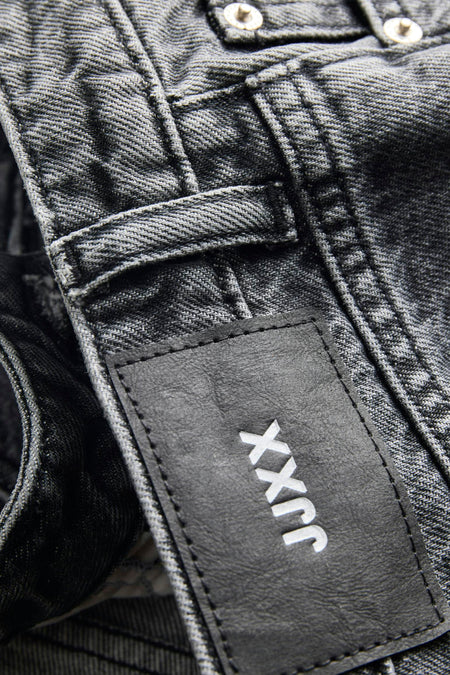Donkergrijze denim korte broek van JJXX met zwart leren label, wit logo en zichtbare knopen.