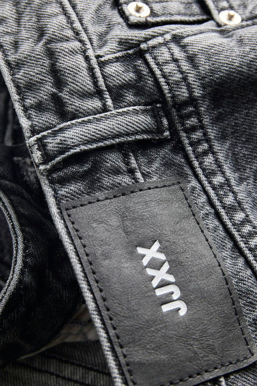 Donkergrijze denim korte broek van JJXX met zwart leren label, wit logo en zichtbare knopen.