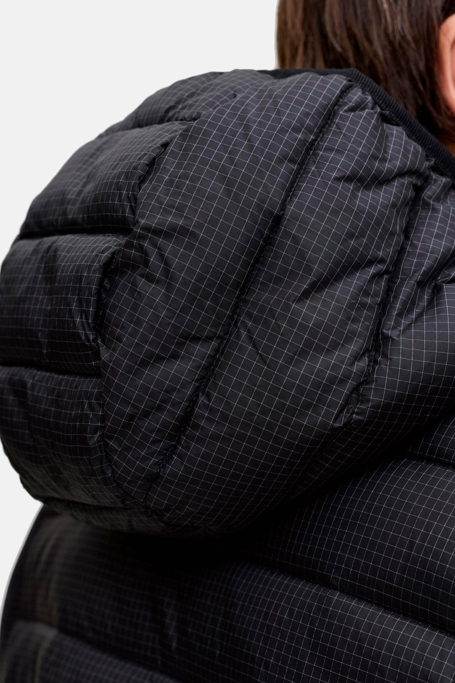 Zwarte gewatteerde jas met ruitpatroon en capuchon.
