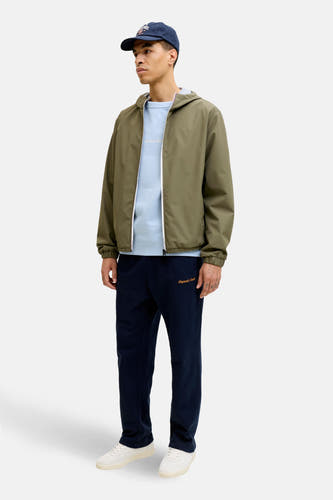 Groene korte jas van ORIGINALS BY JACK & JONES, met lange mouwen en een capuchon, gecombineerd met een blauwe trui en een donkerblauwe broek.