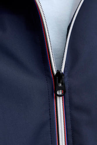 Korte blauwe jas van ORIGINALS BY JACK & JONES, met een witte rits en een rode en blauwe streep langs de rits.