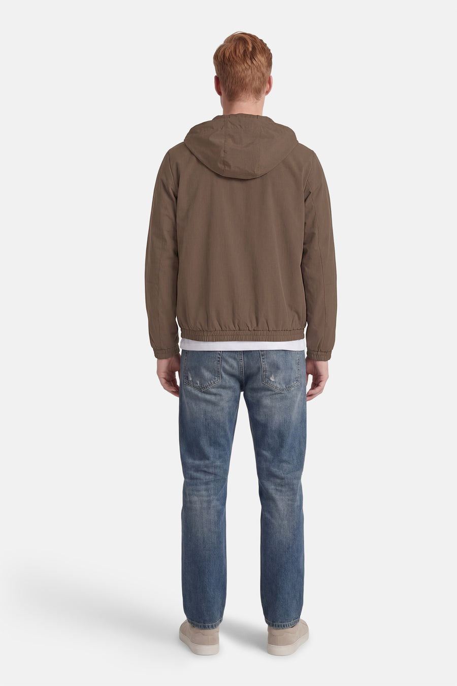 Korte bruine jas van ORIGINALS BY JACK & JONES, met capuchon, gecombineerd met een jeans en sneakers, gezien van achteren.