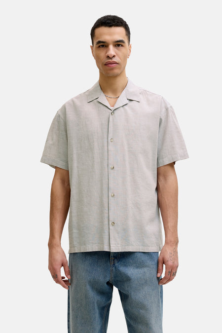 Chemise beige à manches courtes de PREMIUM by JACK & JONES, avec fermeture boutonnée et portée avec un jean bleu.