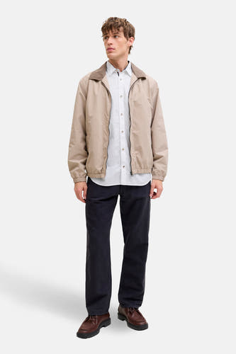 Wit overhemd met lange mouwen van PREMIUM by JACK & JONES, gedragen met een beige jack, zwarte broek en bruine schoenen.