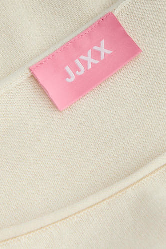 Ecrukleurige trui van JJXX met een fijne breistructuur en een roze merklabel.
