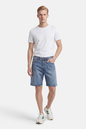 Mid-blauwe jeansshort van JACK & JONES JEANS INTELLIGENCE met knoopsluiting, gedragen door een man met wit T-shirt en sneakers.