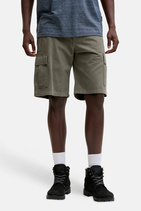 Kaki cargo short van JACK & JONES JEANS INTELLIGENCE, gedragen met een blauw shirt, witte sokken en zwarte laarzen.