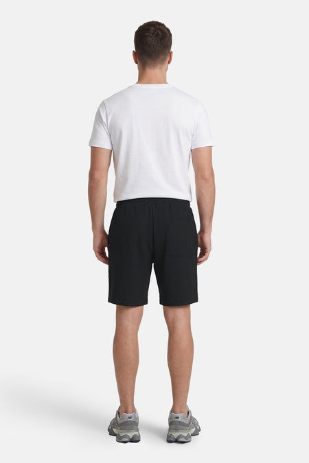 Zwarte ribbelshort van JACK & JONES JEANS INTELLIGENCE, achterkant met zak, model draagt wit T-shirt en grijze sneakers