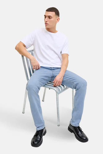 Lichtblauwe slim fit jeans van JACK & JONES JEANS INTELLIGENCE, gecombineerd met een wit T-shirt en zwarte schoenen.