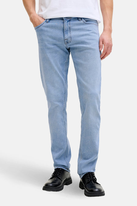 Persoon met lichte jeans en zwarte schoenen.