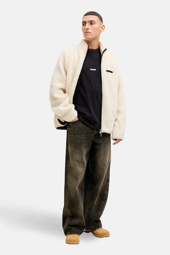 Zwart T-shirt met korte mouwen van CORE BY JACK & JONES, met een klein logo, gedragen onder een teddy vest en wijde jeans met boots.
