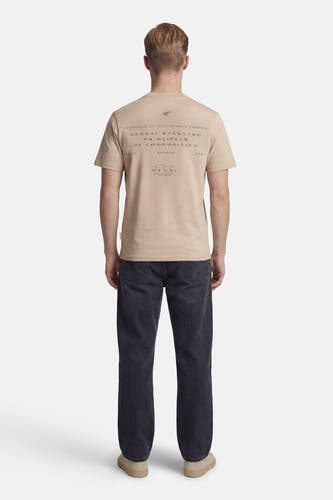 T-shirt beige à manches courtes de CORE by JACK & JONES, avec imprimé texte au dos, combiné avec un jean foncé et des chaussures beiges.
