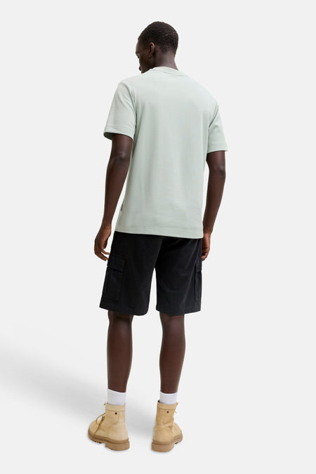 Groene korte mouwen t-shirt van CORE BY JACK & JONES, achterzijde, lichtgroen, eenvoudig design, model draagt zwarte cargo shorts en beige laarzen