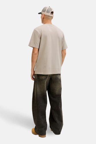Beige T-shirt met korte mouwen van CORE BY JACK & JONES, losse pasvorm, gedragen met een pet en wijde jeans.