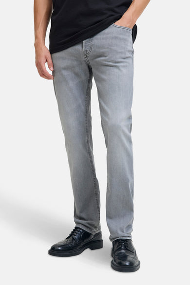 Lichtgrijze slim jeans van JACK & JONES JEANS INTELLIGENCE, met een zwarte top en zwarte schoenen.