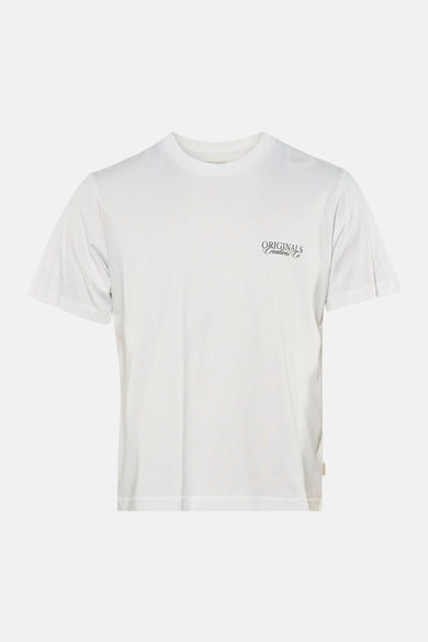 T-shirt blanc à manches courtes de ORIGINALS BY JACK & JONES, avec un petit logo sur la poitrine, porté avec un jean déchiré.