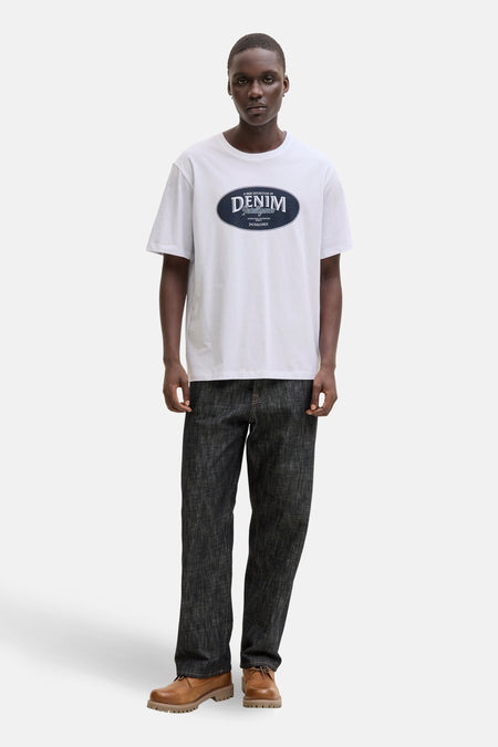 Wit T-shirt met korte mouwen van ORIGINALS by JACK & JONES, met opdruk op de borst, gecombineerd met een donkere jeans en bruine schoenen.