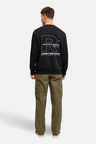 Zwarte sweater van JJREBEL met witte grafische print op de rug, gecombineerd met olijfgroene cargo broek.