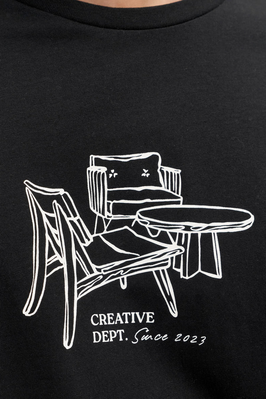 T-shirt noir à manches courtes de JJREBEL, avec illustration blanche de meubles et le texte "Creative Dept. Since 2023".