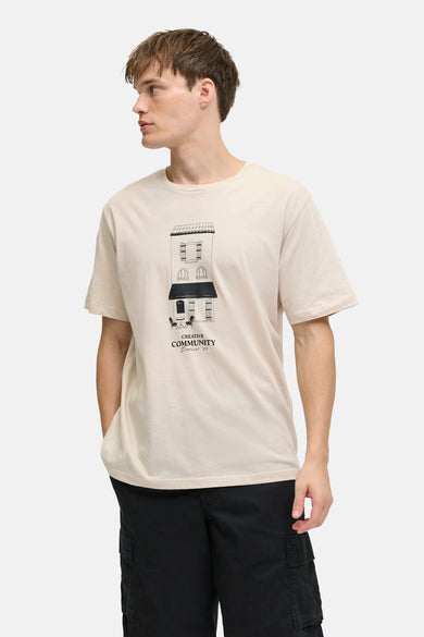 T-shirt beige à manches courtes de JJREBEL, avec un imprimé de bâtiment et porté avec un pantalon noir.