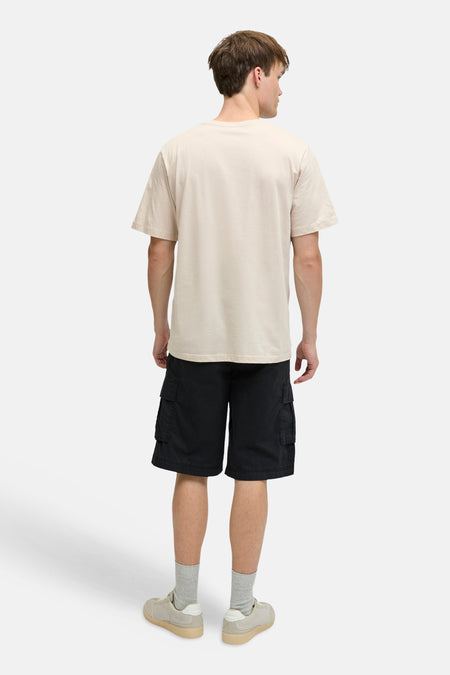 T-shirt beige à manches courtes JJREBEL, vu de dos, associé à un short noir et des chaussettes grises.