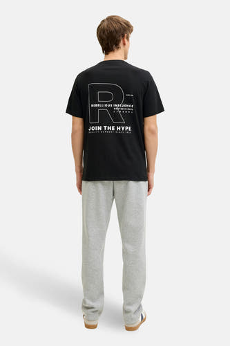T-shirt noir à manches courtes de JJREBEL, avec un grand imprimé blanc dans le dos et un jogging gris.