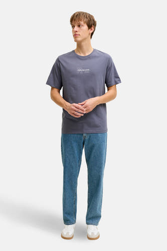 Blauw T-shirt met korte mouwen van JJREBEL, met een kleine print op de borst, gecombineerd met blauwe jeans en witte sneakers.
