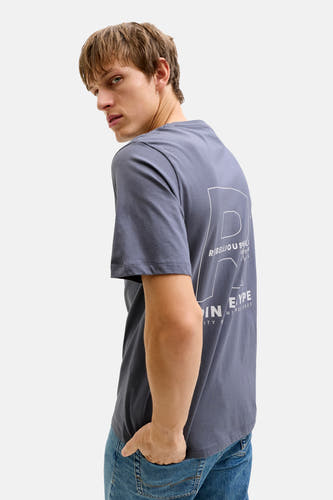 Blauw T-shirt met korte mouwen van JJREBEL, met witte print op de achterkant en gedragen met jeans.
