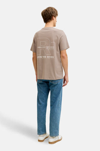 T-shirt marron à manches courtes de JJREBEL, avec imprimé blanc au dos, combiné avec un jean bleu et des baskets blanches.