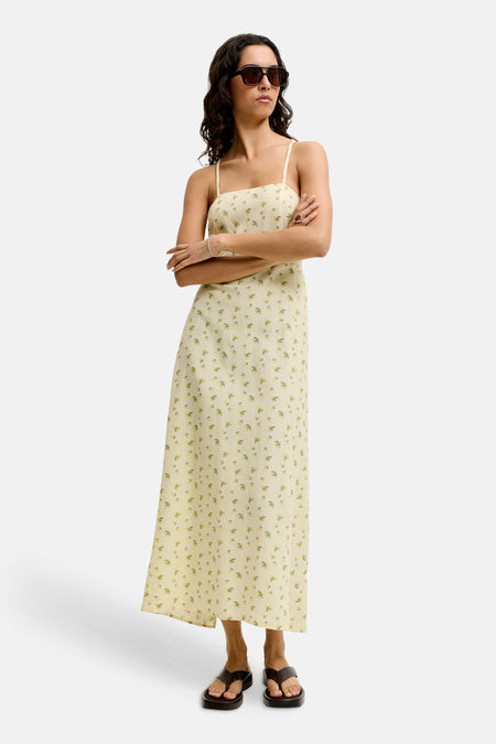 Geel mouwloos maxi-kleedje van JJXX met ruitjespatroon en bloemenprint, gedragen door een model met zonnebril.