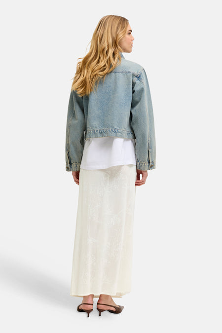 Jupe longue blanche de JJXX avec motif ajouré en tricot, portée avec une veste en jean et un t-shirt blanc, vue de dos.