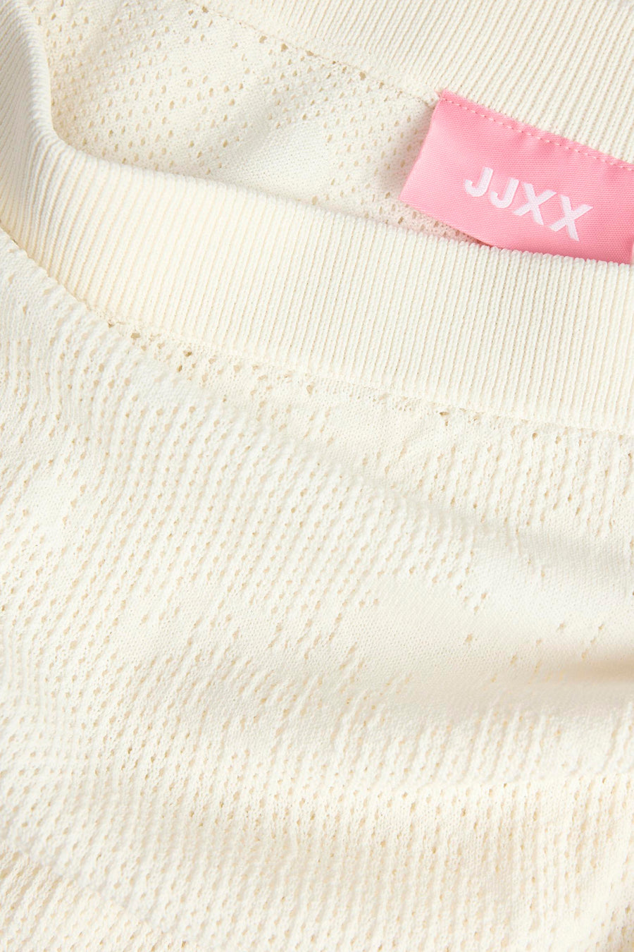 Witte rok van JJXX met ajourpatroon, geribbelde rand en roze label, in close-up.