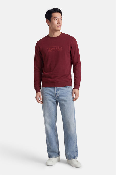 Rode sweater met ronde hals van ORIGINALS BY JACK & JONES, met tekstprint op de borst, gecombineerd met jeans en witte sneakers.
