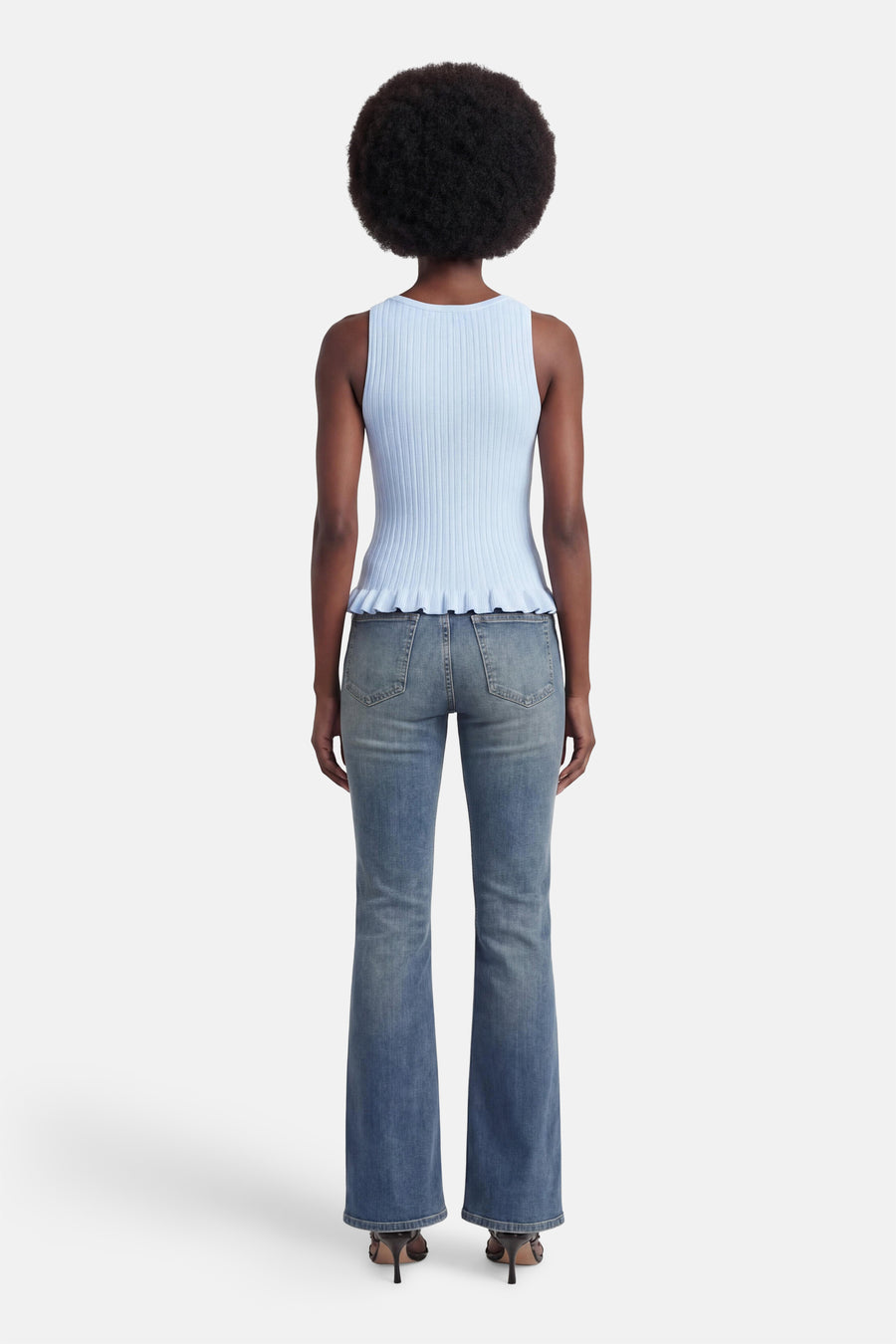 Blauwe ribgebreide top van JJXX met peplumzoom, gedragen met flared jeans, in rugweergave.