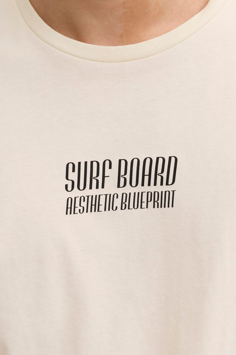 T-shirt écru de JJREBEL avec texte noir "Surf Board Aesthetic Blueprint", gros plan du haut du corps.