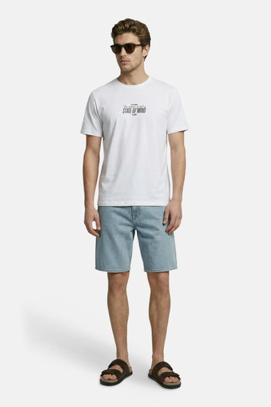 Wit T-shirt van JJREBEL, met korte mouwen en een kleine tekstprint, gedragen met denim shorts en sandalen.
