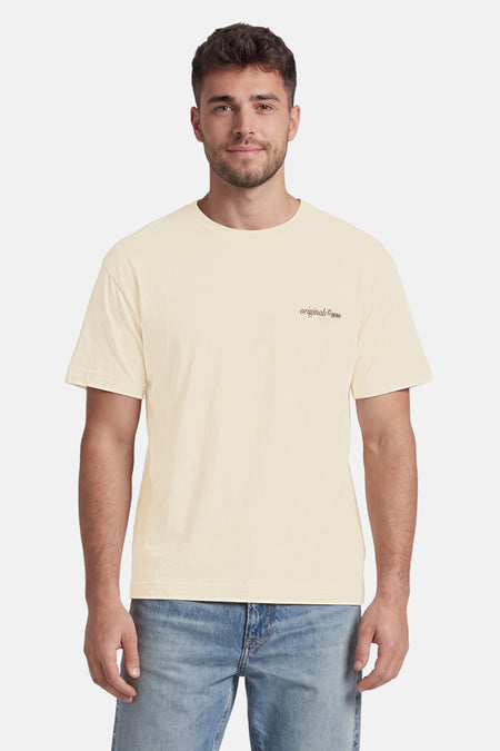 T-shirt beige de ORIGINALS BY JACK & JONES avec col rond, manches courtes et petit imprimé 'originals ©1990' sur la poitrine, porté par un homme.