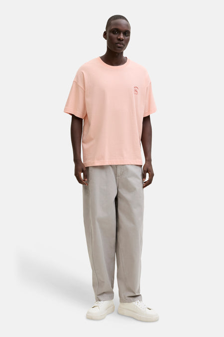 T-shirt rose de ORIGINALS BY JACK & JONES, avec un petit imprimé sur la poitrine et porté avec un short gris.