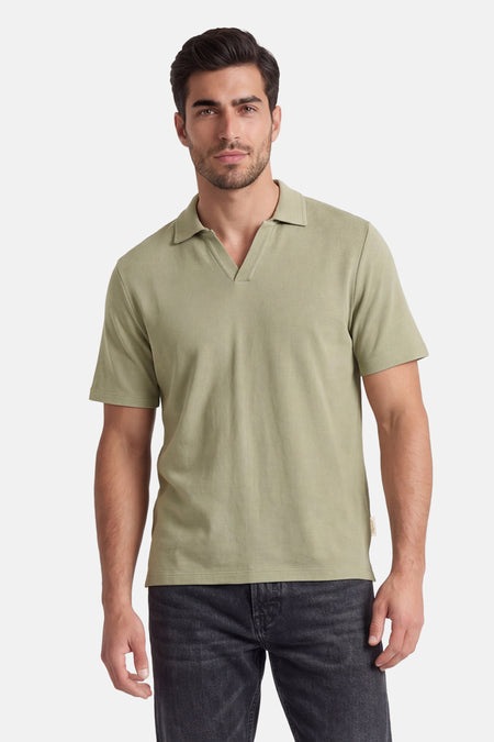 Polo verte ORIGINALS BY JACK & JONES de couleur verte avec col en V, portée par un homme en jean foncé.