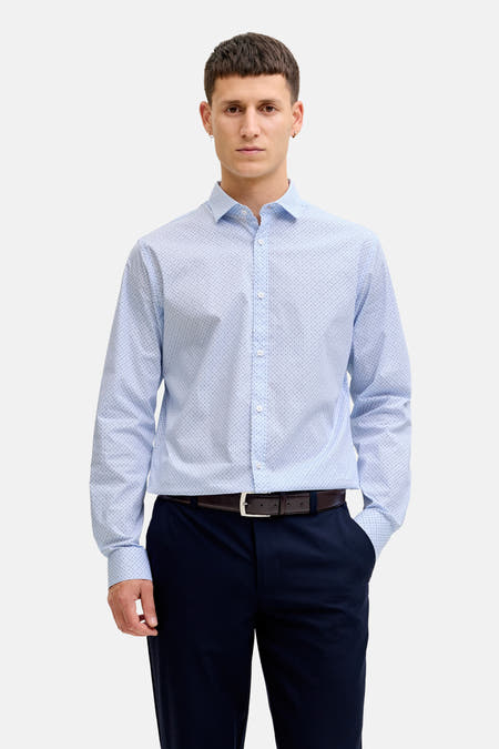 Chemise bleue à manches longues de PREMIUM by JACK & JONES, avec un motif à petits pois fins, combinée avec un pantalon foncé et des chaussures en cuir.