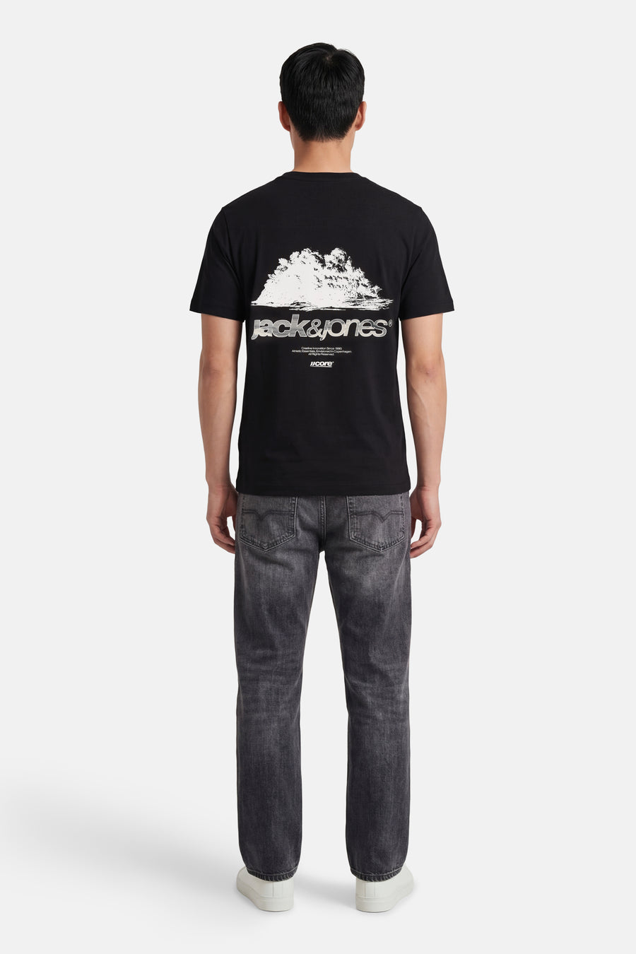 T-shirt noir de CORE BY JACK & JONES avec imprimé graphique blanc et logo dans le dos, porté par un homme.