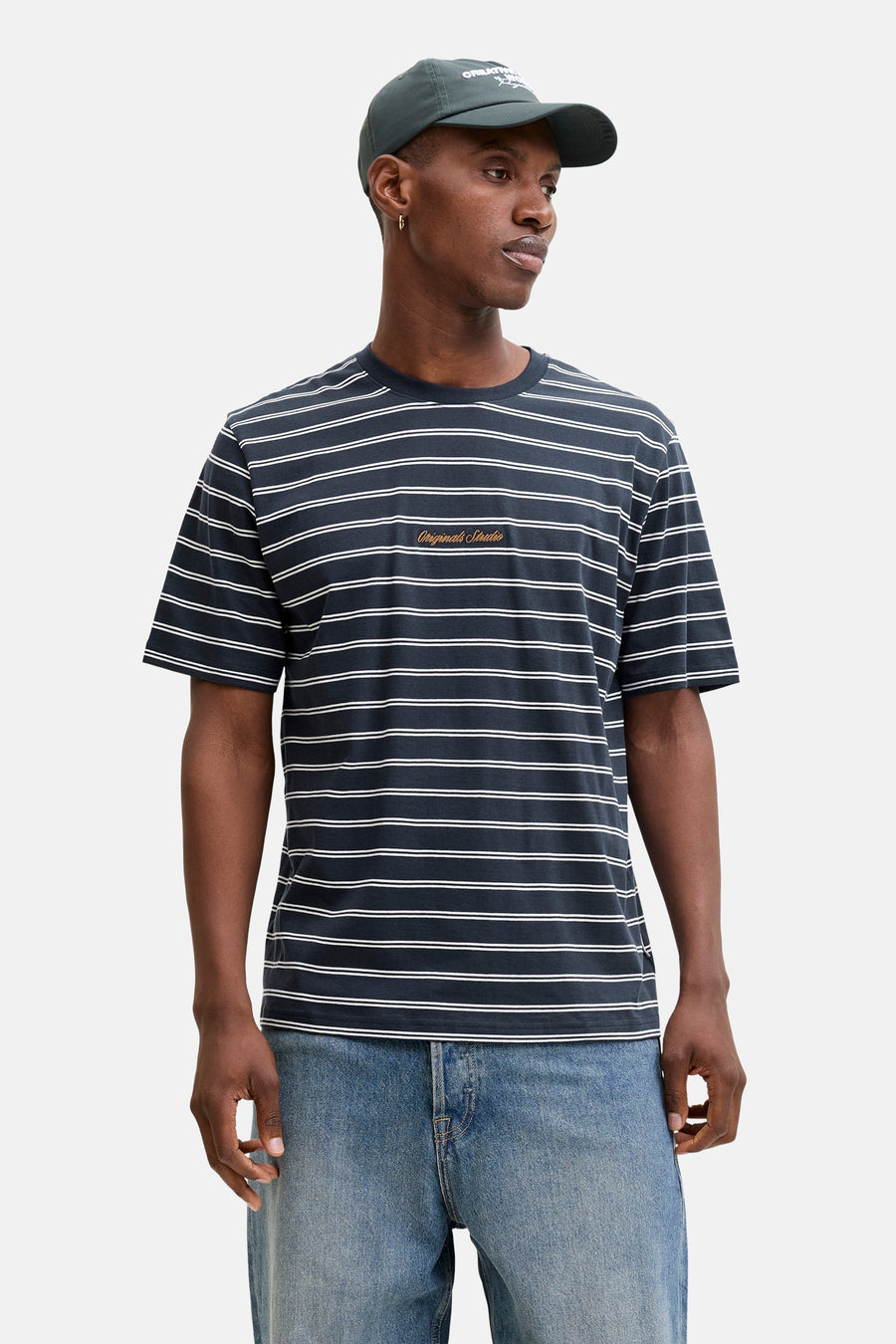 Blauw gestreept T-shirt met korte mouwen van ORIGINALS BY JACK & JONES, met geborduurde tekst en gedragen met een groene pet en jeans.
