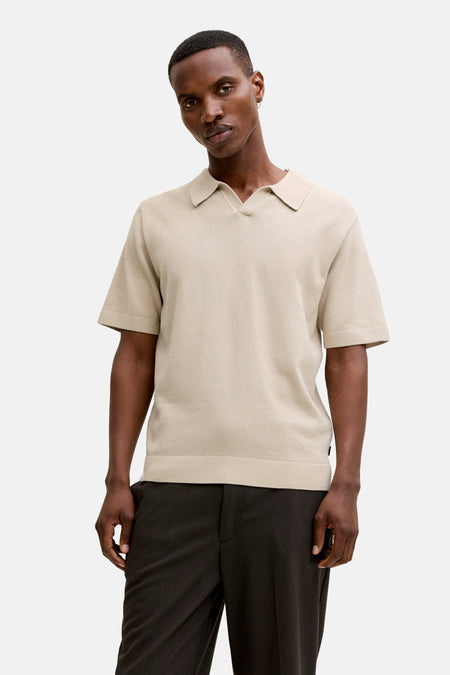 Beige polo met korte mouwen van PREMIUM by JACK & JONES, met subtiele textuur en gedragen met donkere pantalon.
