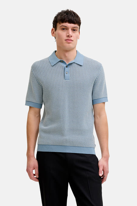 Polo bleu de PREMIUM by JACK & JONES, avec un motif chiné subtil, combinée avec un pantalon noir et des chaussures marron.
