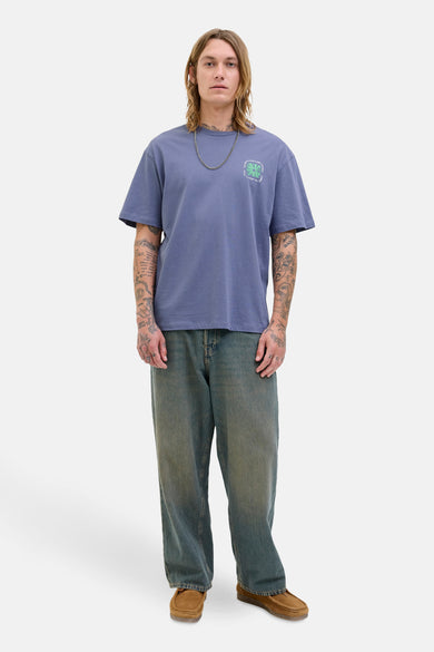 T-shirt bleu à manches courtes d'ORIGINALS BY JACK & JONES, avec une impression sur la poitrine et porté avec une chaîne en argent.