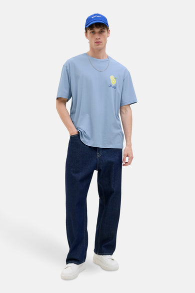 Blauw T-shirt met korte mouwen van Originals by Jack & Jones, met citroen ontwerp, gedragen met donkere jeans en witte sneakers.

